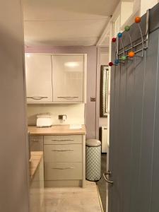 una pequeña cocina con armarios blancos y una encimera en Coastal Cabin Chalet, en Roch