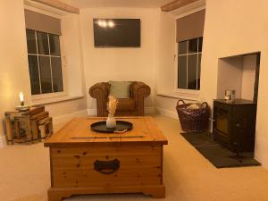 a living room with a coffee table and a chair at Cosy country cottage with log fireplace and views in Kendal