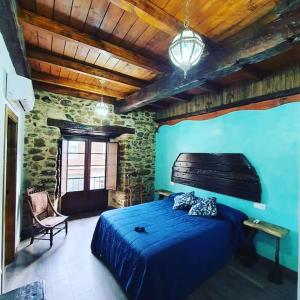 a bedroom with a blue bed and a stone wall at Hostal La Medina de Camponaraya in Camponaraya