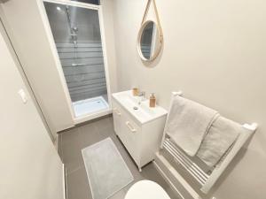 biała łazienka z umywalką i lustrem w obiekcie Le Schongauer w mieście Colmar