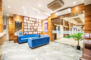 a lobby with a blue couch and a glass wall at Hotel Bhabha in Rajkot