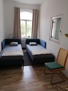 Zimmer mit 2 Betten, einem Stuhl und einem Fenster in der Unterkunft Alberthof Zittau in Zittau