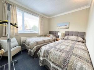 1 dormitorio con 2 camas y ventana en 2 bedroom chalet bungalow on Humberston Fitties. en Humberston