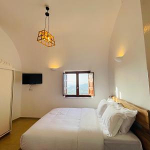 a bedroom with a white bed and a window at Diva Santorini Luxury Villa in Pyrgos