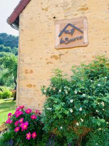 a sign on the side of a building with flowers at Gîte La Source in Grusse