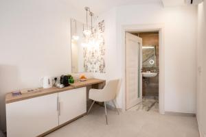 a kitchen with white cabinets and a table and a chair at Vela Blu Boutique Suites in Il-Gżira