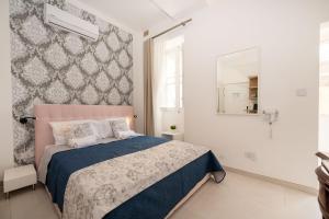 a bedroom with a blue and white bed and a mirror at Vela Blu Boutique Suites in Il-Gżira