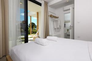 a bedroom with a white bed and a balcony at NiSea Beach Apartments in Prinos