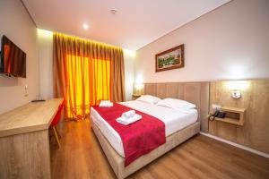 ein Schlafzimmer mit einem großen Bett mit einer roten Decke in der Unterkunft CLASS Hotel in Ksamil