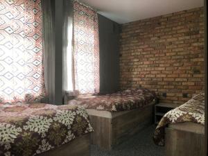 a bedroom with two beds and a brick wall at Гостевой Комплекс ARTек in Tamchy
