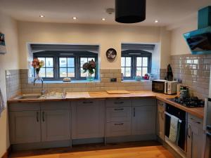 a kitchen with white cabinets and a counter top at Cosy cottage in the Blackdown Hills Devon in Honiton