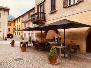 eine Terrasse mit Tischen und Sonnenschirmen im Innenhof in der Unterkunft Mamma Ciccia in Mandello del Lario