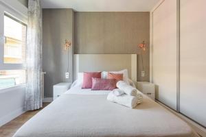 1 dormitorio con 1 cama blanca grande con almohadas rosas en Apartamento centrico parking aire acondicionado y wifi, en Granada