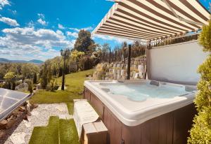una bañera de hidromasaje en un patio trasero con sombrilla en Luxus Resort - Zupko en Fiľakovo