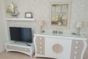 a living room with a tv on a white dresser at APARTAMENTO PLAYA FOZ CON TERRAZA in Foz