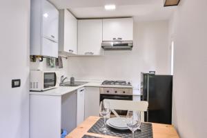 a kitchen with white cabinets and a table with glasses on it at [CENTRO-LECCO] Romantico Appartamento sul Lago in Lecco