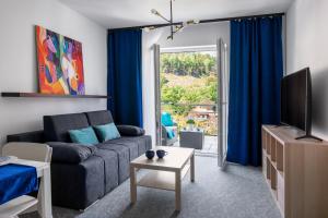 a living room with a couch and a tv at Apartamenty Wczasowa - komfort z rowerownią in Kudowa-Zdrój