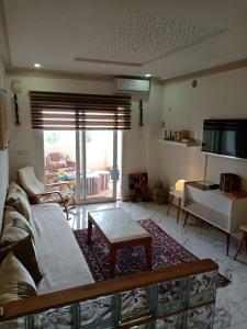 a living room with a couch and a table and a tv at bel appart dans une résidence avec piscine, à 750m de la plage. Confort garanti. in Saidia 
