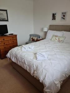 a bedroom with a large white bed and a dresser at Our House in Nairn