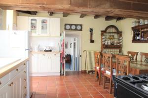 a kitchen with white cabinets and a red tile floor at La Maison du Passeur in Availles-Limouzine