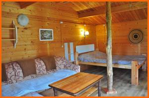 ein Wohnzimmer mit einem Sofa und einem Bett in einer Hütte in der Unterkunft Campsite Leiputrija in Ādaži