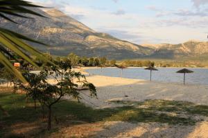 a beach with umbrellas and a mountain in the background at Asteri Apartments Mytikas 2-Bedroom Seaview Courtyard in Mitika