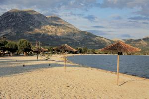 a beach with straw umbrellas and water and mountains at Asteri Apartments Mytikas 2-Bedroom Seaview Courtyard in Mitika