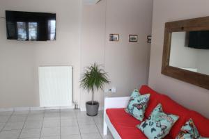 un soggiorno con divano rosso e pianta di Asteri Apartments Mytikas 2-Bedroom Seaview Courtyard a Mýtikas