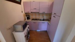 uma pequena cozinha com armários cor-de-rosa e um micro-ondas em Residence Euroville em Germignaga