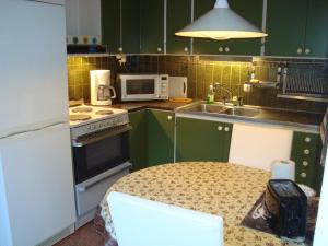 una cocina con armarios verdes y una mesa con microondas en 2 room apartment, en Ystad