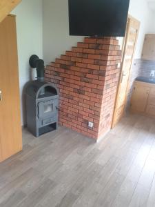 a brick fireplace in a room with a stove at Domek w Bieszczadach u Ani Apartament 2 in Orelec