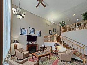 a living room with a staircase with chairs and a table at Quality Inn in Mitchell