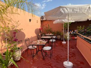 Un patio con mesas y sillas y una sombrilla. en Riad Malfa, en Marrakech