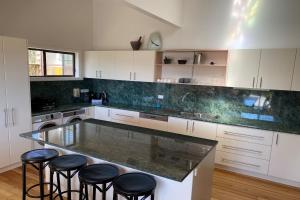 a kitchen with a large counter with stools around it at HIDDEN HAVEN Binalong Bay in Binalong Bay