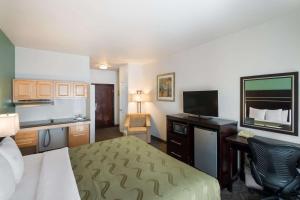 a hotel room with a bed and a desk and a television at Quality Inn & Suites Airport West in Salt Lake City