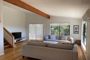 a living room with a couch and a tv at HIDDEN HAVEN Binalong Bay in Binalong Bay
