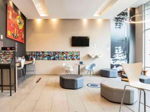 a waiting room with chairs and a tv on a wall at Hotel Ibis Cali Granada in Cali