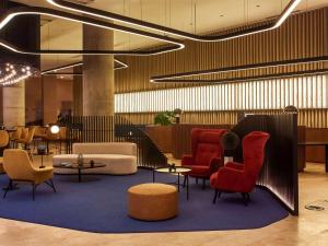 a lobby with red chairs and tables in a building at Pullman Lima San Isidro in Lima