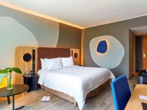 a bedroom with a bed, chair, table and a lamp at Pullman Lima San Isidro in Lima
