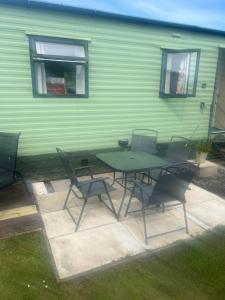 a patio with a table and chairs in front of a green building at Mountain View in Millom