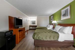 a hotel room with a bed and a flat screen tv at Quality Inn - Roxboro South in Roxboro