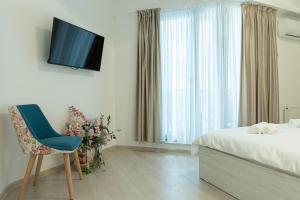 a bedroom with a bed and a tv and a chair at Apartament Le Bonheur Deux Solid Residence Butoaie in Mamaia