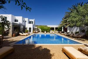 a large swimming pool with lounge chairs in front of a house at Petit Andromeda Mykonos I in Mikonos