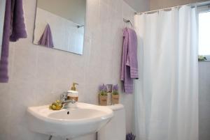 a bathroom with a sink and a white shower curtain at Anemomylos Apartments in Lixouri