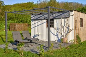 twee stoelen onder een pergola naast een schuur bij Reetdachhaus De Ole Kaat in Niesgrau