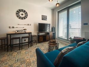 ein Wohnzimmer mit einem blauen Sofa, einem Tisch und einer Uhr in der Unterkunft Apartament TURKUS in Puck