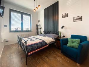 ein Schlafzimmer mit einem Bett und einem blauen Stuhl in der Unterkunft Apartament TURKUS in Puck