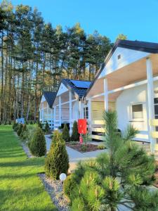 a home with a yard with trees and bushes at Nadmorska Przystan Domki - Basen, sala zabaw, rowery, animacje in Ustka