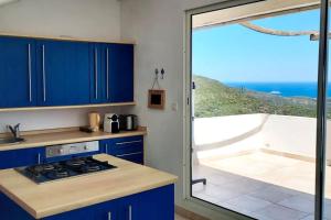 Rogliano Maison de charme avec vue panoramique في Rogliano: مطبخ مع دواليب زرقاء وإطلالة على المحيط