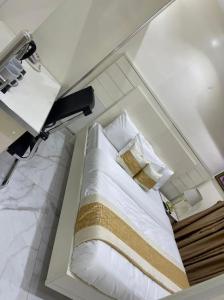 um quarto com uma cama com lençóis brancos e almofadas em LUXOL HOMES&SUITES em Ikeja